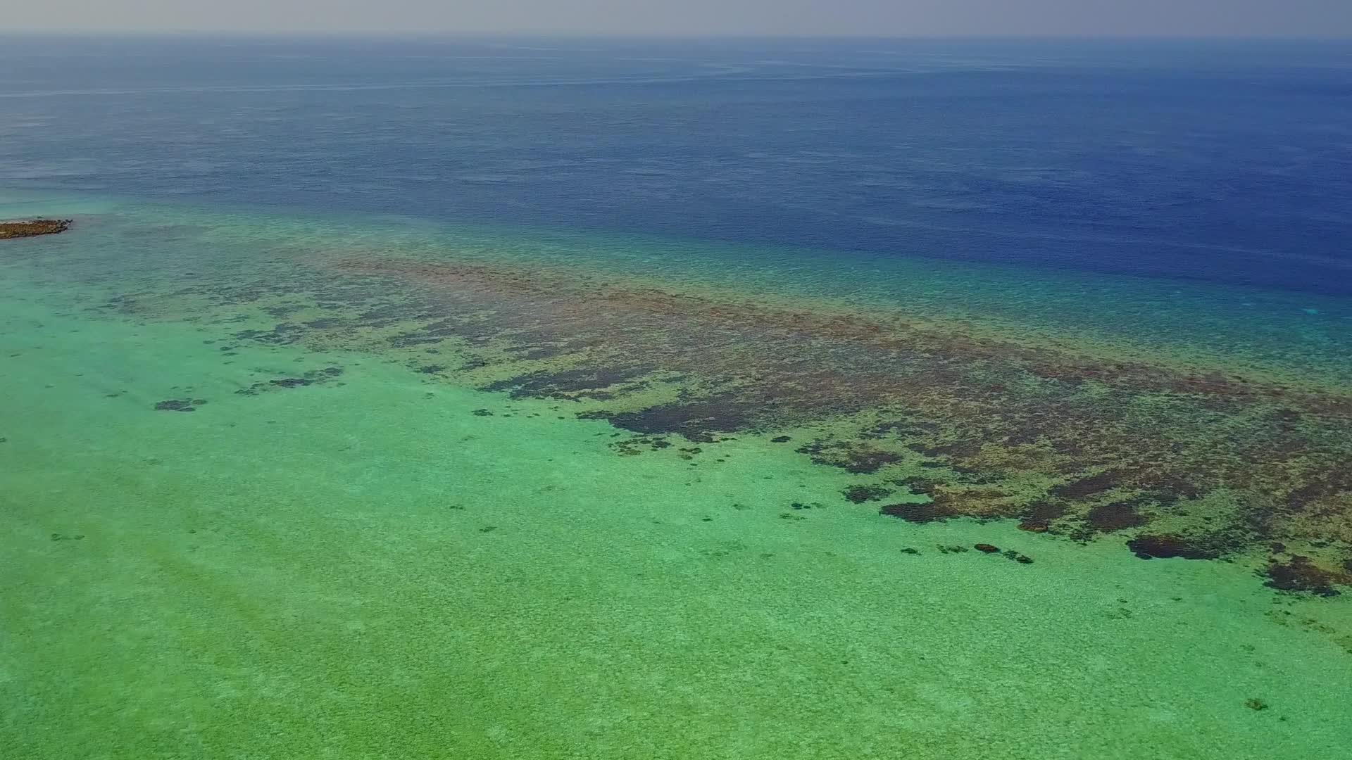蓝色海滨环绕着海平面和冲浪附近的浅沙背景视频的预览图
