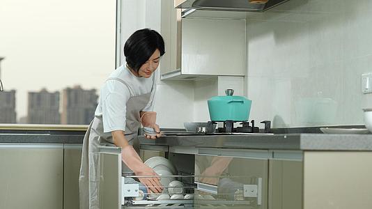 主妇把洗好的盘子放在碗柜里视频的预览图