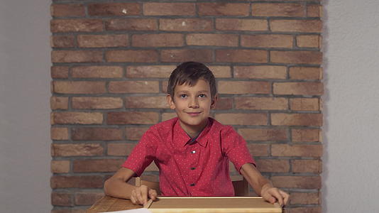 孩子们坐在桌子上在背景红砖墙上写着自由字母视频的预览图