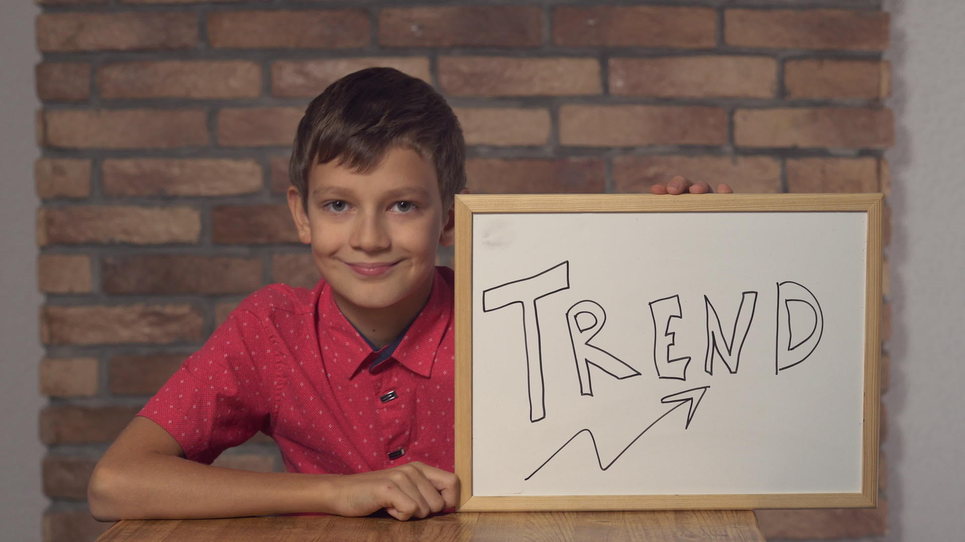 孩子们坐在桌子上手里拿着一张纸背面的红砖墙有字母的趋势视频的预览图
