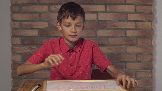 坐在桌子上的孩子拿着翻页图上的红砖墙上面写着一百万视频的预览图