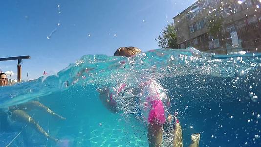 快乐的女伴在温泉游泳池里快乐地游泳冲向相机慢动作视频的预览图