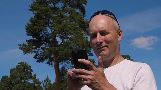 浏览夏季森林绿松树背景下的手机校对Portnos视频的预览图
