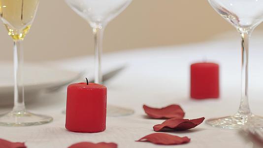 男服务员或情人为浪漫晚餐点亮红色爱情蜡烛餐桌上的餐桌上有红色的爱情蜡烛视频的预览图