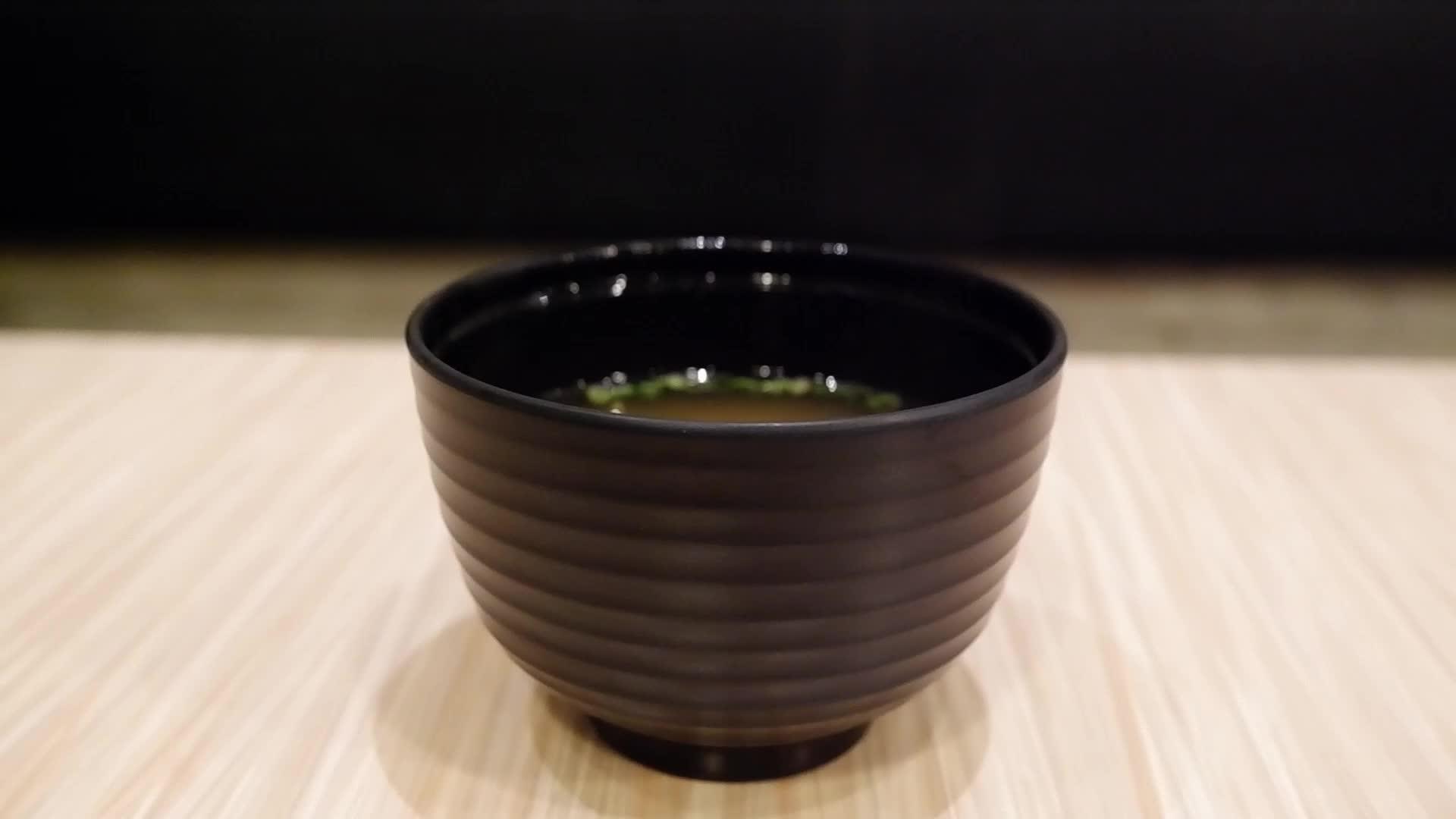 用手打开黑汤杯盖和漂浮在木桌上的白烟视频的预览图