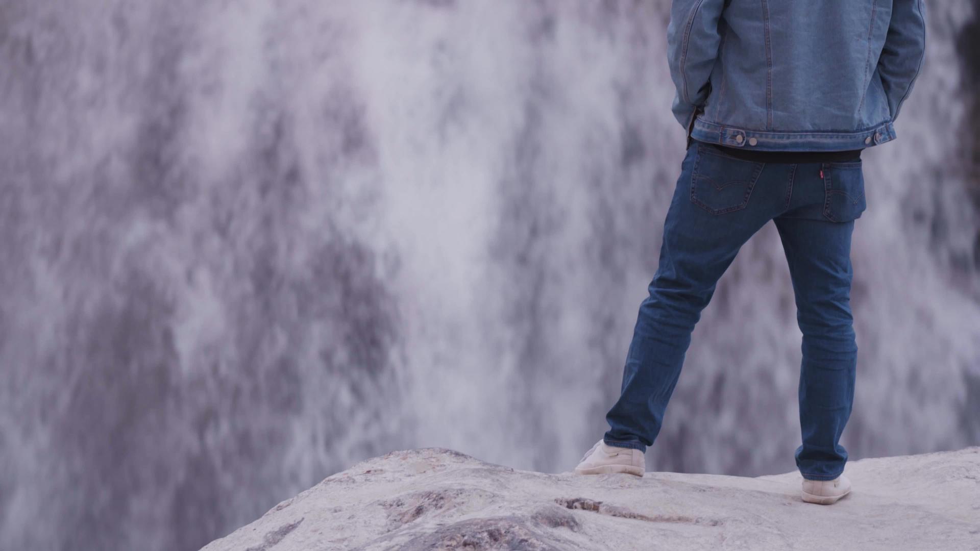 印度年轻人站在岩石上穿着蓝色牛仔夹克和蓝色牛仔裤视频的预览图