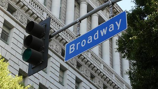 百老汇街的地名标志和美国支柱上的红绿灯在市中心的道路上视频的预览图