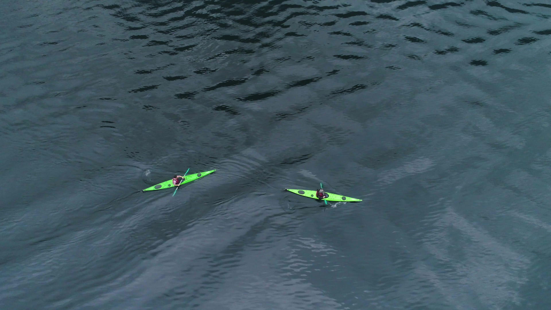 北北极湾的绿色水面上有两艘绿色皮艇从上到下垂直于空中视频的预览图