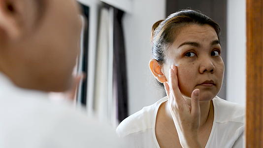 亚洲中年女性看着镜子里的皱纹视频的预览图