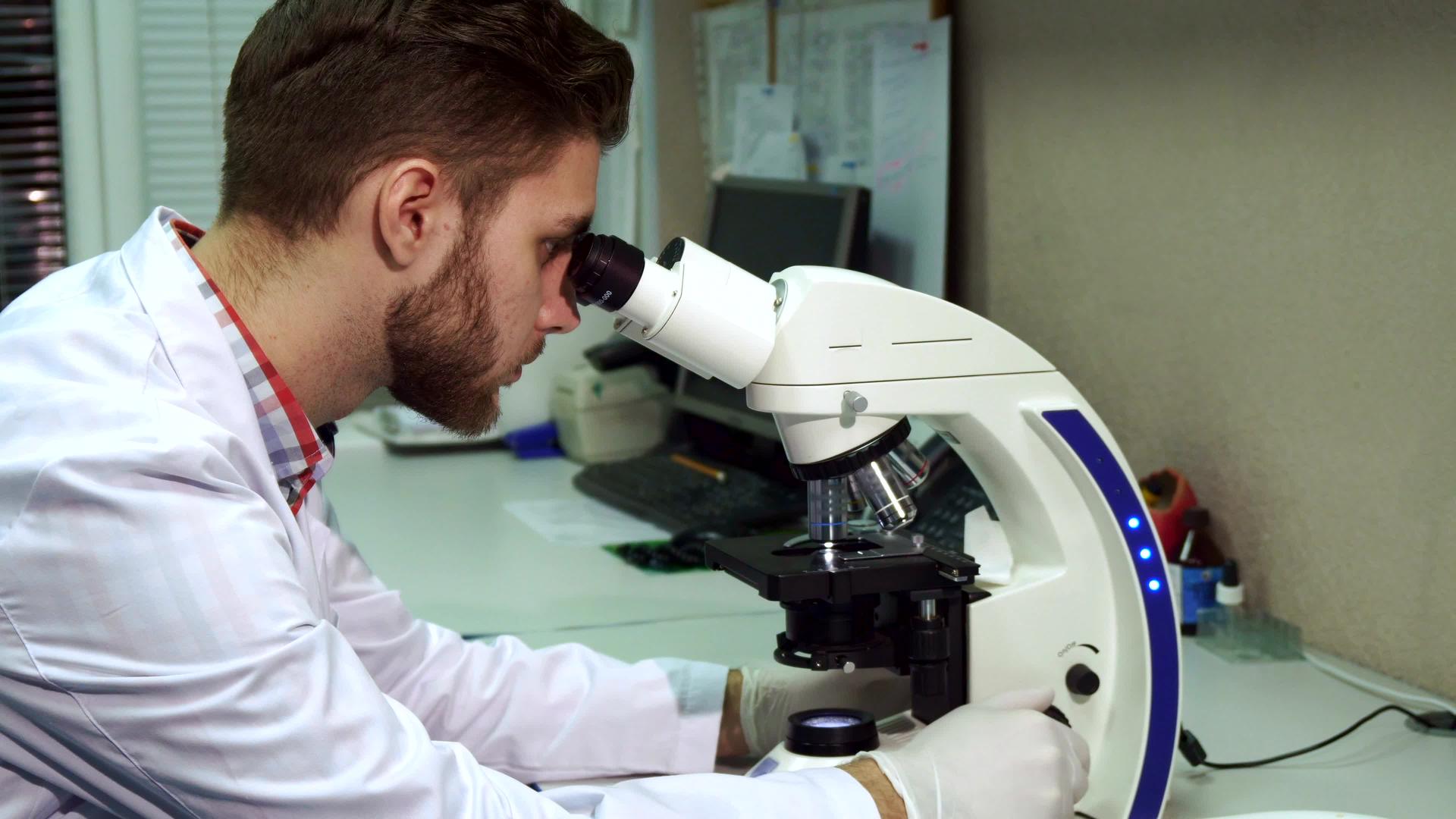男人通过实验室的显微镜看人视频的预览图
