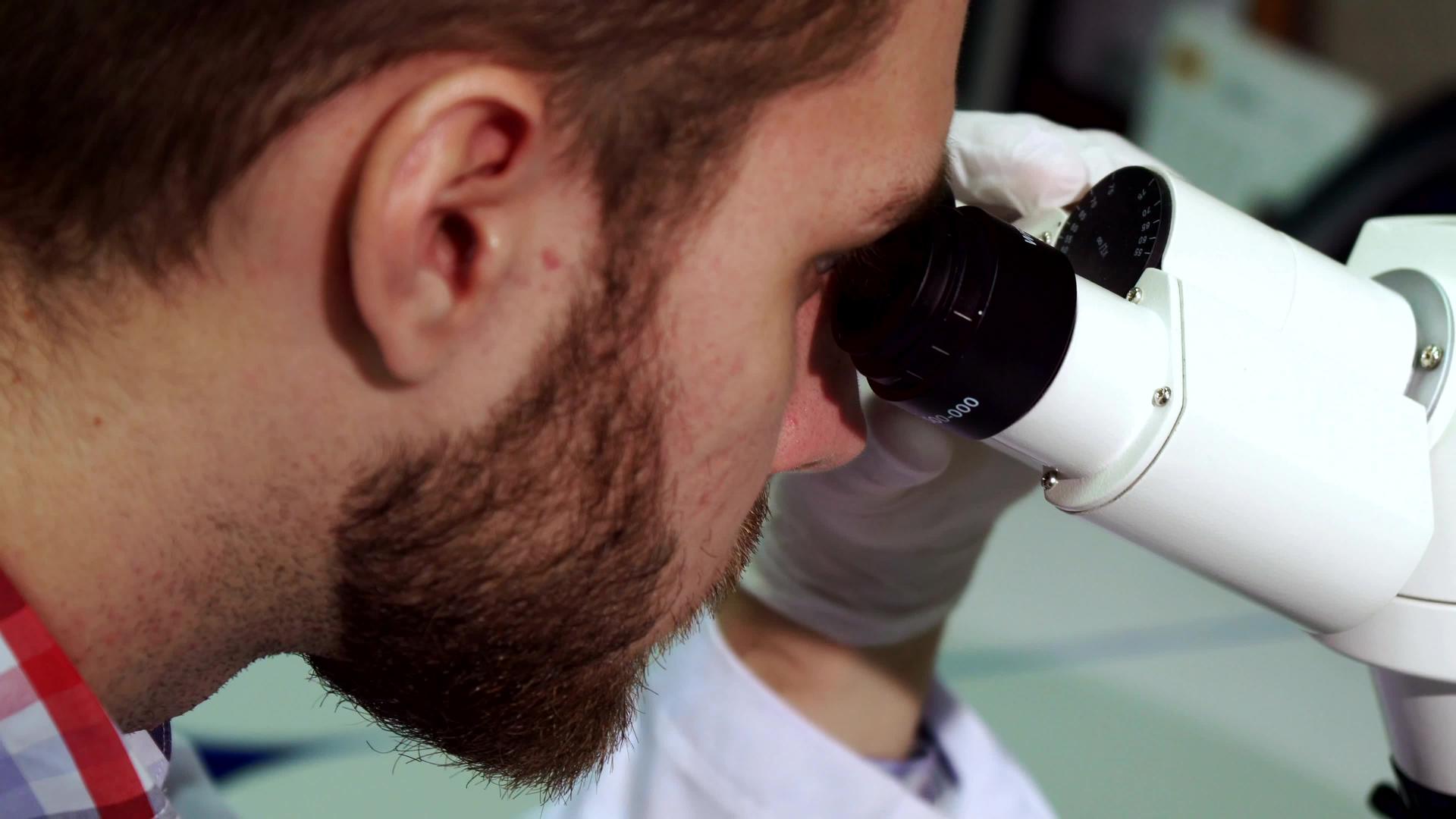实验室里的男人看着显微镜眼镜视频的预览图