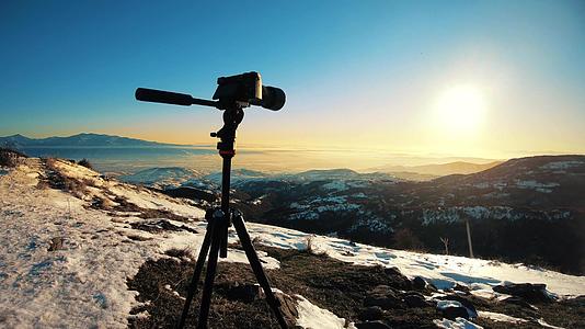 摄影师在冬季风景中折叠相机的三脚架摄影师视频的预览图