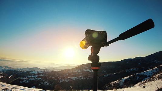 摄影师用相机和三脚架拍摄黄昏时的美景视频的预览图