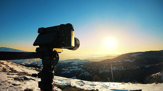 在山顶的三脚架上拍摄冬季日落的照片视频的预览图