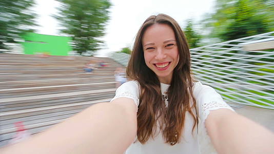 年轻女孩制作视频自拍在公园里玩耍年轻积极的女人很开心视频的预览图