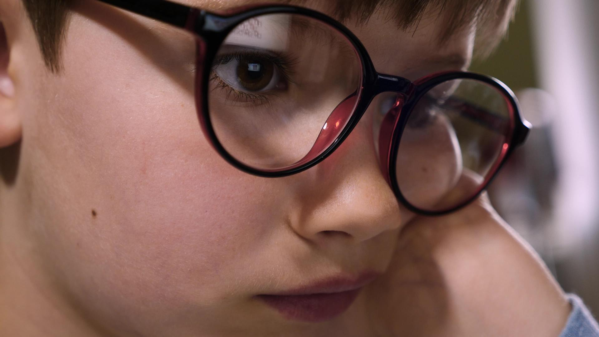 聪明的孩子戴着眼镜在电脑前学习近距离面对孩子使用互联网视频的预览图