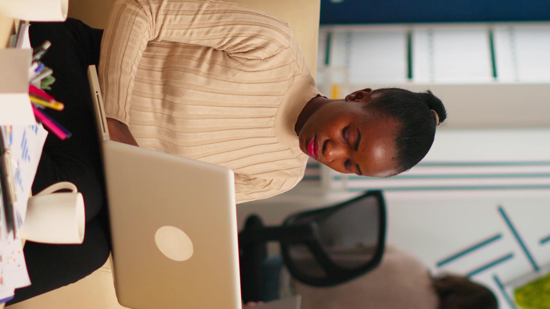 非裔美国女士在笔记本电脑上写作看着相机微笑视频的预览图