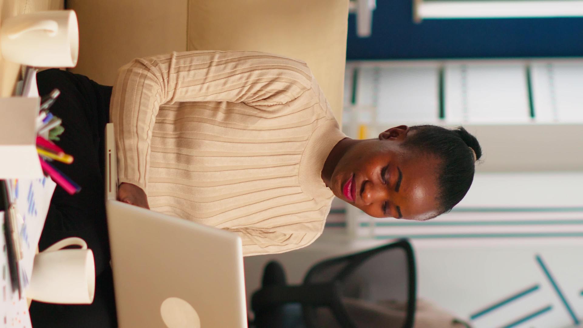 在笔记本电脑上打字的非洲女性肖像看着镜头微笑着视频的预览图