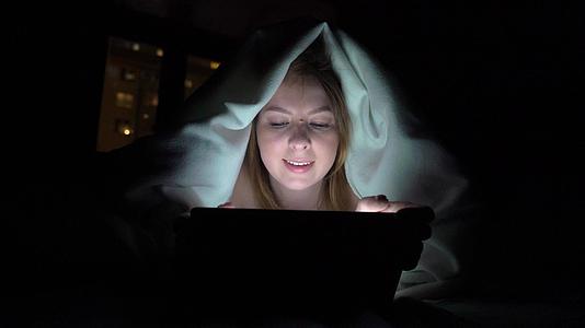 年轻女性在睡觉前在床上使用平板药物即手机成瘾者的概念视频的预览图