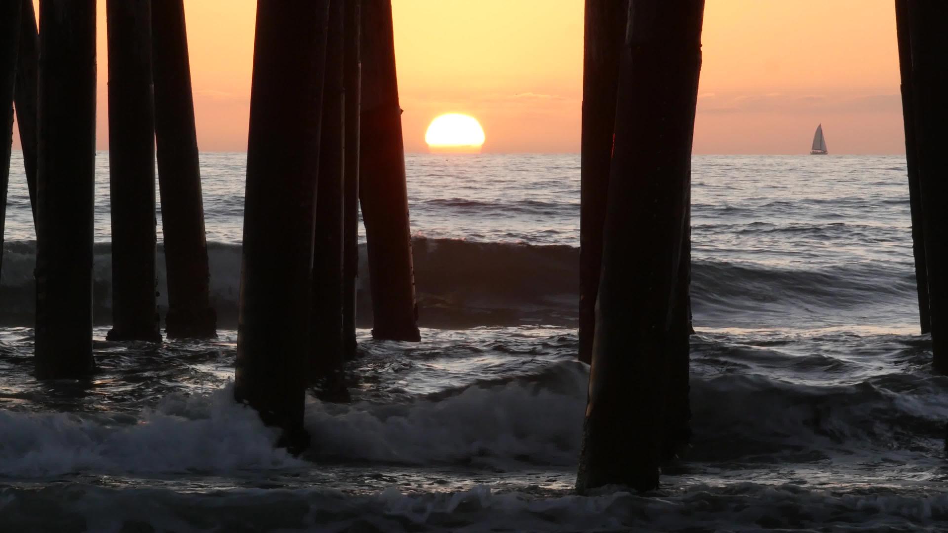 海水、太阳和木材堆积物而海边的日落则倾泻在水中视频的预览图