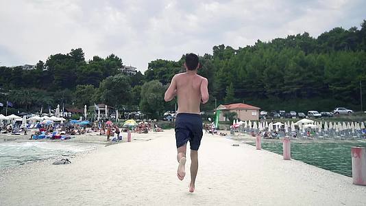 年轻人赤脚在海滩码头慢跑电影风景慢动作视频的预览图