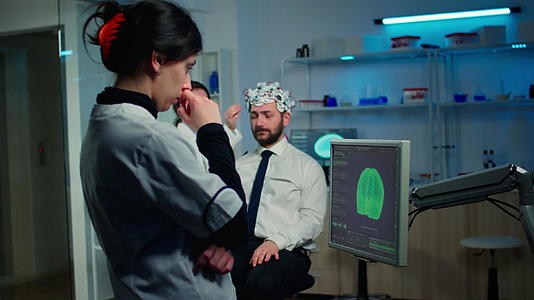 女性研究人员在监测器中分析大脑扫描视频的预览图