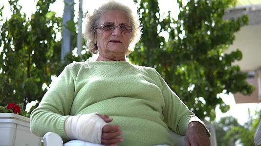 老年妇女受伤双手断了手臂断了坐着说话视频的预览图