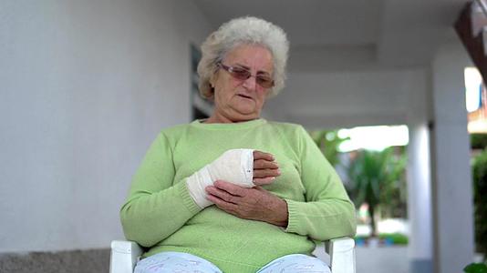 悲伤的老妇人坐在绷带里把手放在绷带里视频的预览图