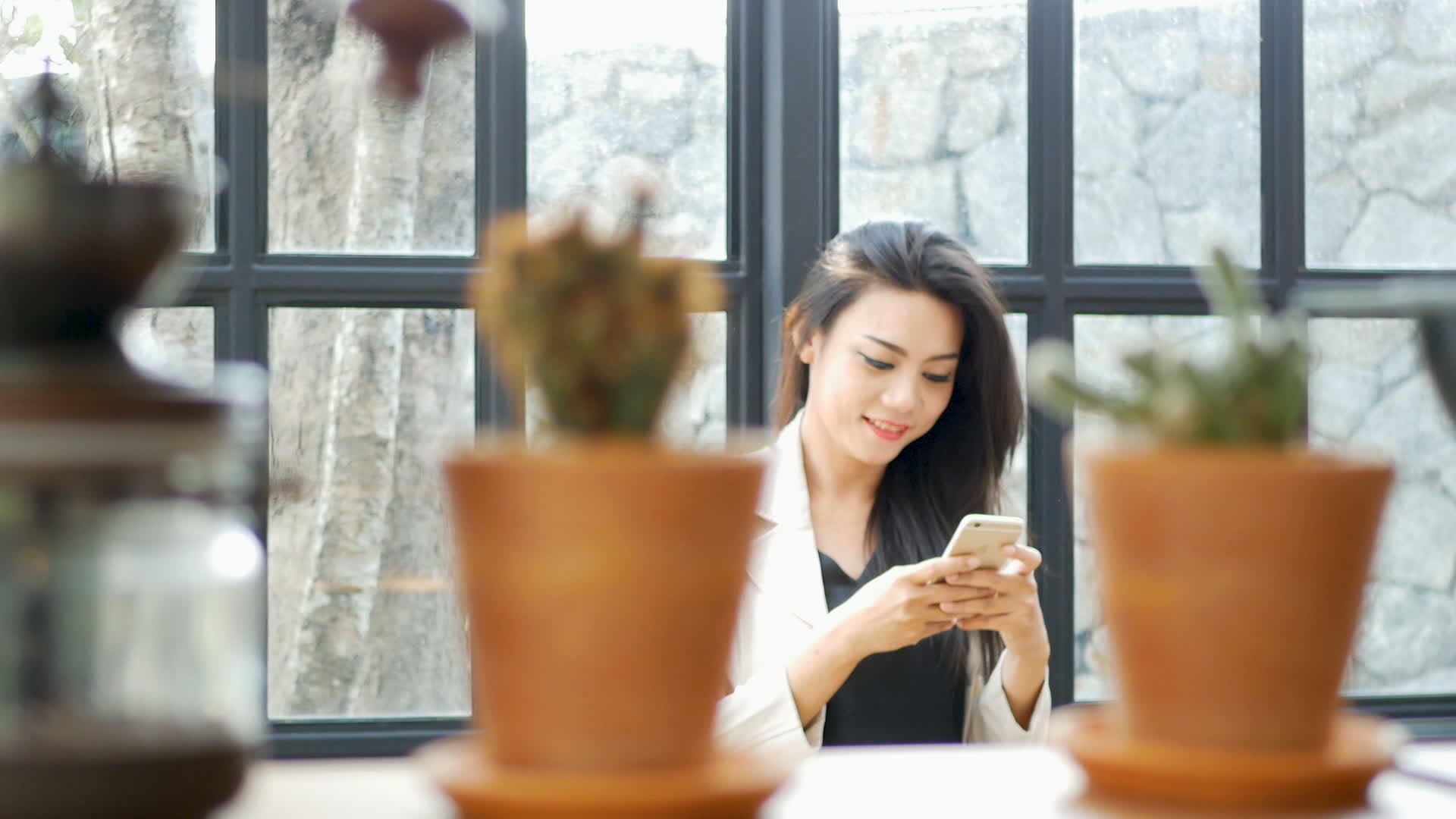 美丽的亚洲年轻女商人穿着西装和外套在智能手机上使用应用程序视频的预览图