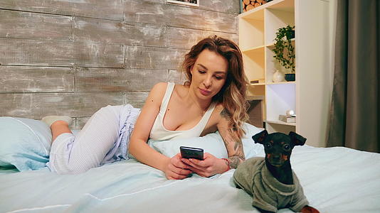 穿着睡衣的美女用她的手机视频的预览图