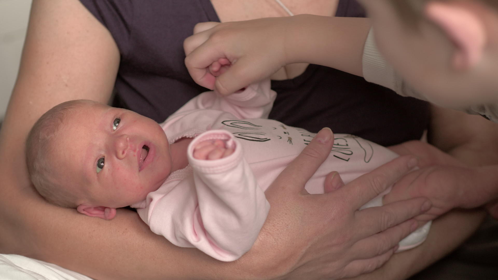 有新生儿的奶奶和弟弟抚摸婴儿手的弟弟视频的预览图