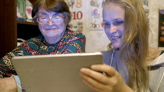 年轻女性和年长女性在墙上看照片视频的预览图