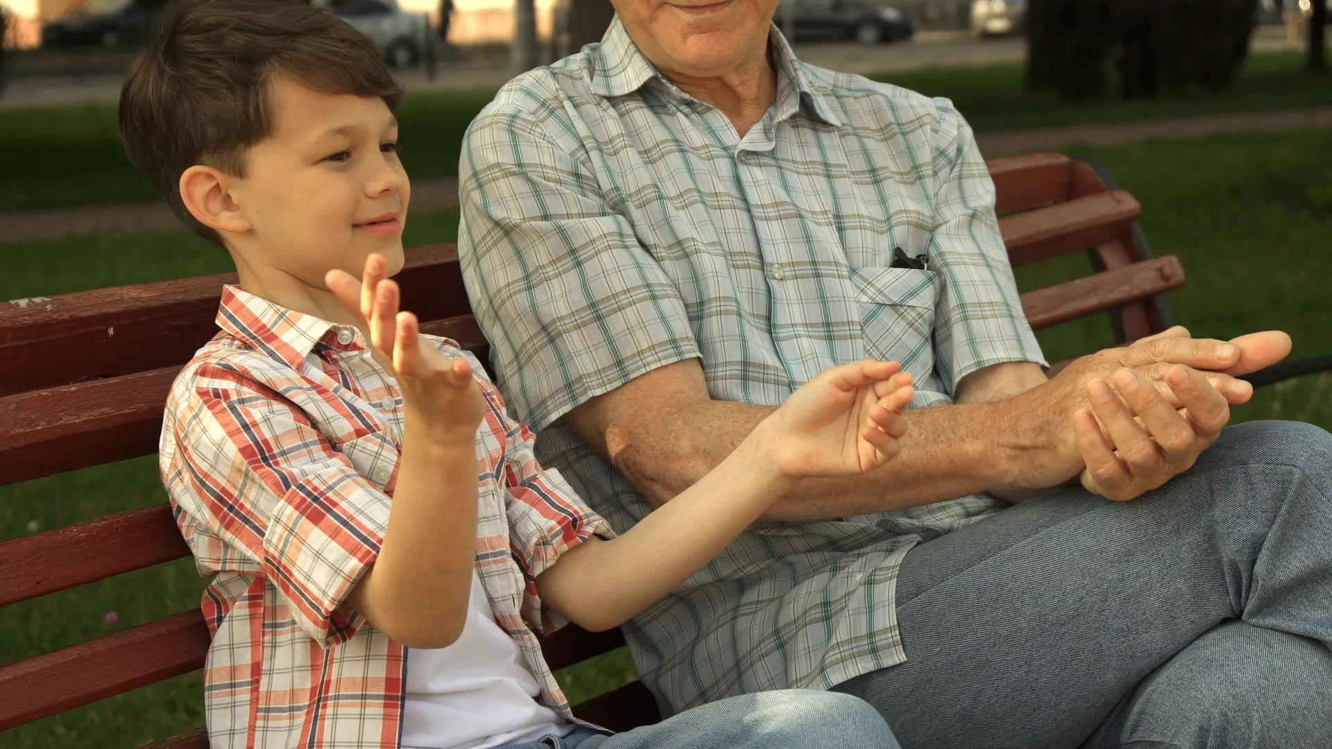 高个子男人和他的孙子在板凳上玩视频的预览图