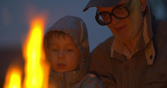老人和小男孩坐在营火附近视频的预览图