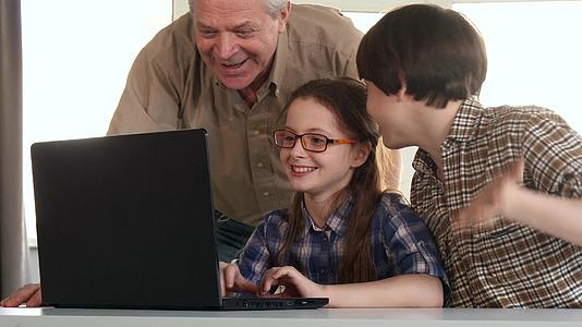 老人和孙子在笔记本电脑上娱乐视频的预览图