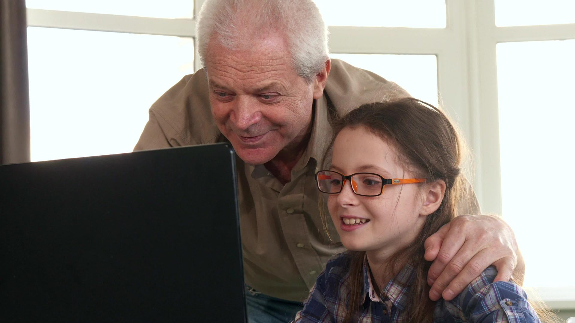 小女孩和她的祖父在笔记本电脑上有视频聊天视频的预览图