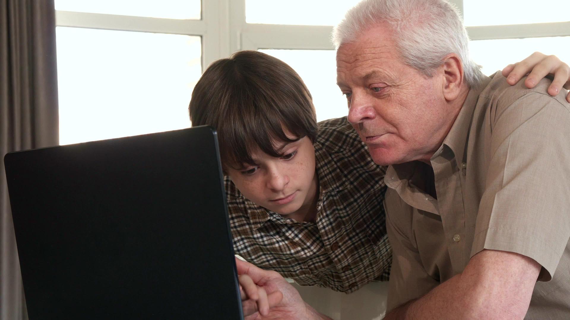 小男孩用笔记本电脑帮助他的祖父视频的预览图