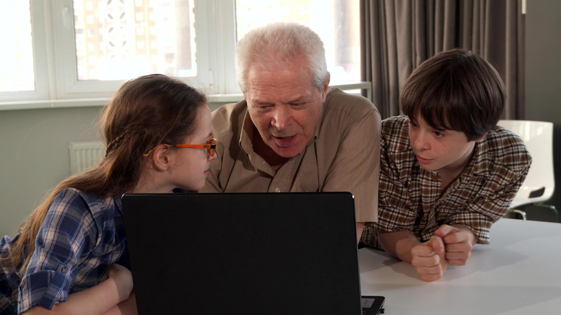 他们的孩子和爷爷在笔记本电脑上看东西视频的预览图