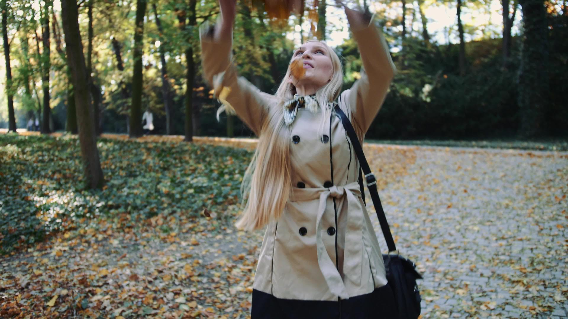 秋天年轻女孩在公园里散步在空中慢慢地扔金叶视频的预览图
