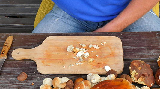 用老手上的菜刀清洗野生蘑菇小心地从茎上取蘑菇视频的预览图