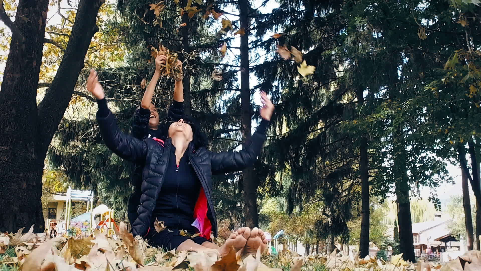 赤脚妈妈和儿子坐在秋天的公园里玩得很开心女人把它扔在空中视频的预览图