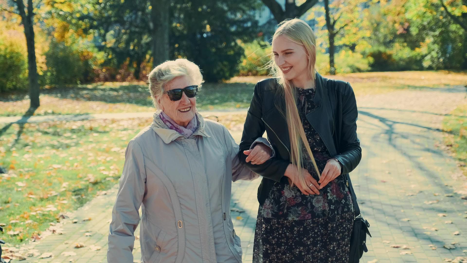 老妇人和快乐的金发女孩在秋天的公园里散步视频的预览图