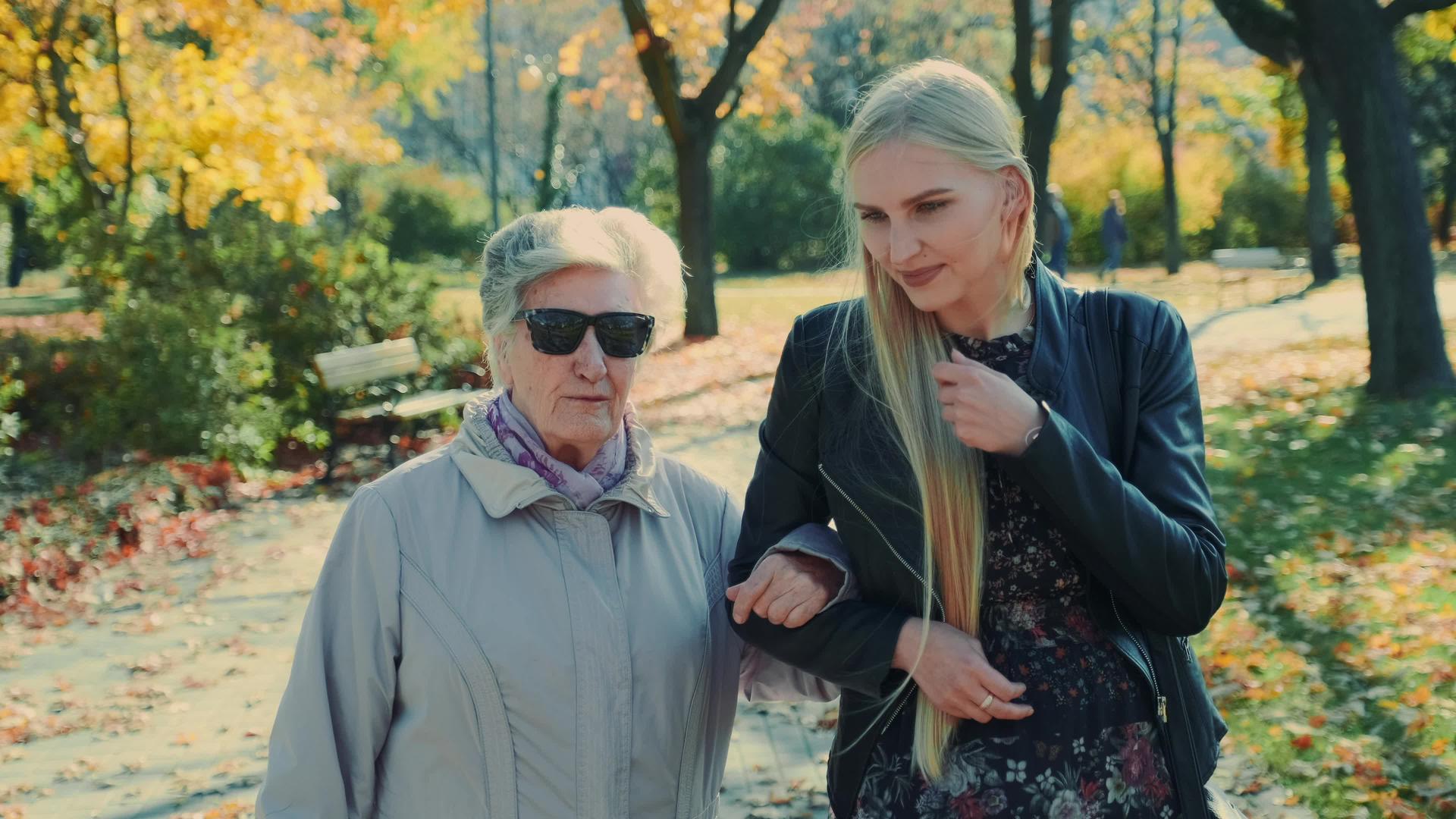 老妇人和快乐的金发女孩在秋天的公园里散步视频的预览图