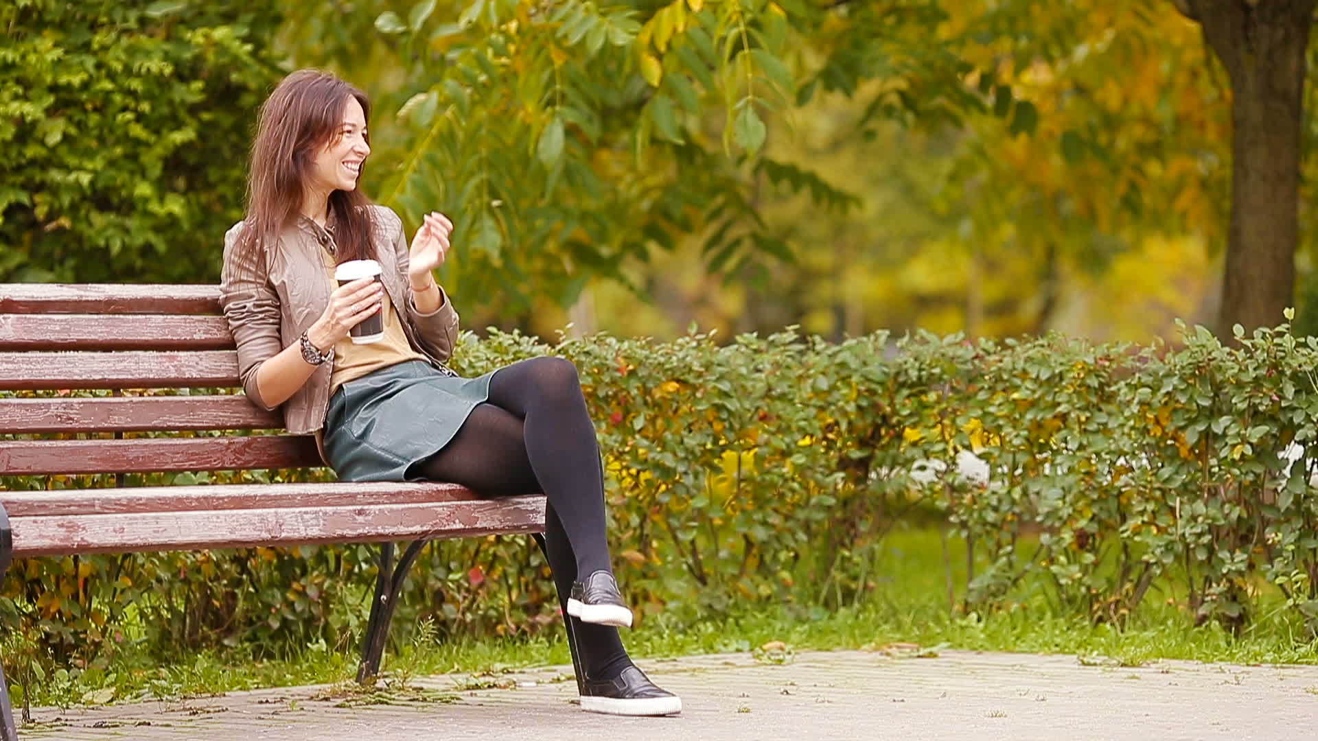 美丽的女人在秋天的公园里喝咖啡在秋天的树叶下喝咖啡视频的预览图