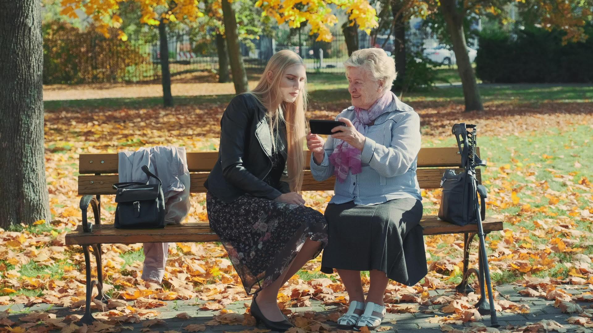 漂亮的金发女郎年长的女士坐在椅子上智能手机视频的预览图
