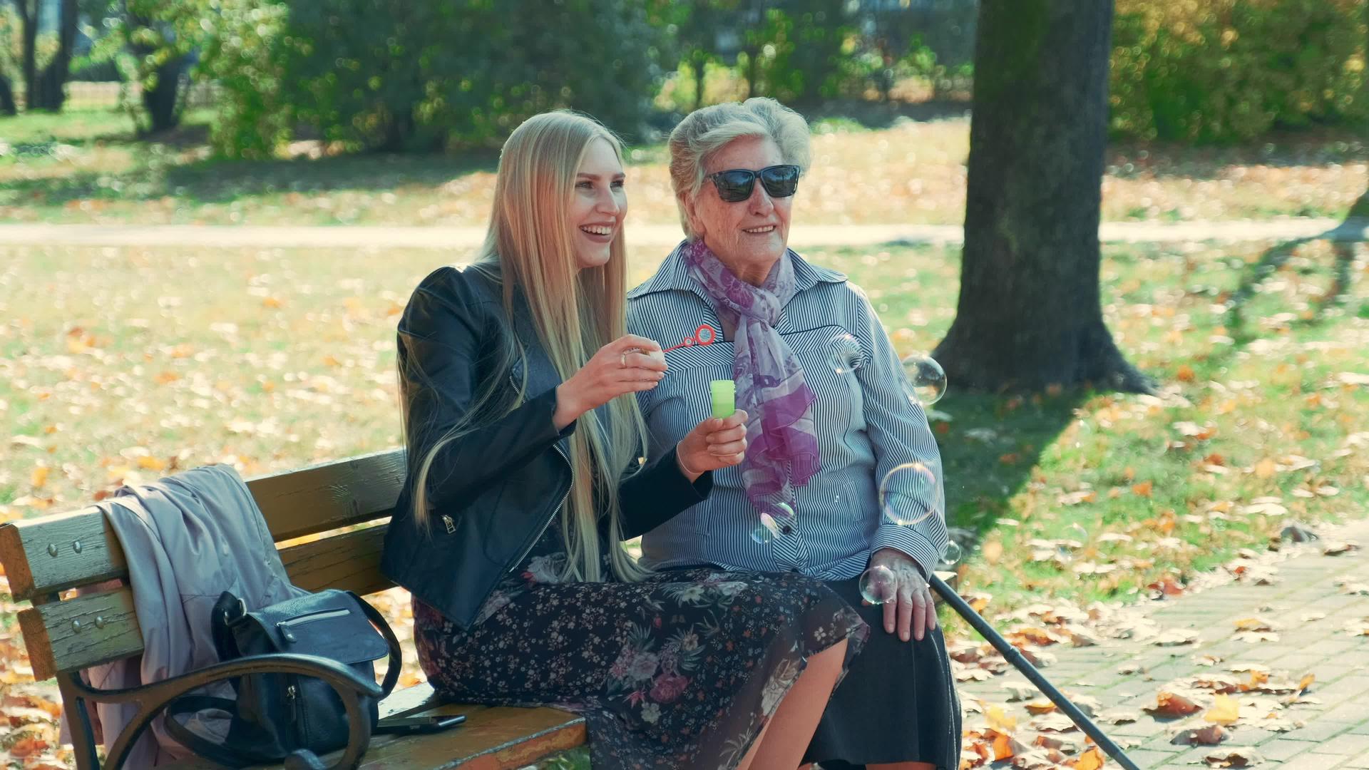 一个快乐的年轻女子坐在公园里和奶奶坐在一起视频的预览图