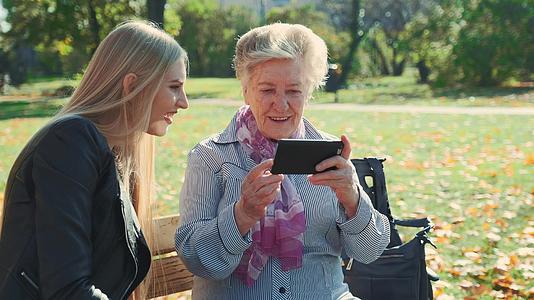大奶奶在智能手机上展示孙女的照片请看她孙女的照片视频的预览图