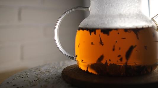 在玻璃茶壶里泡红茶的特写镜头茶在灯光下玩耍视频的预览图