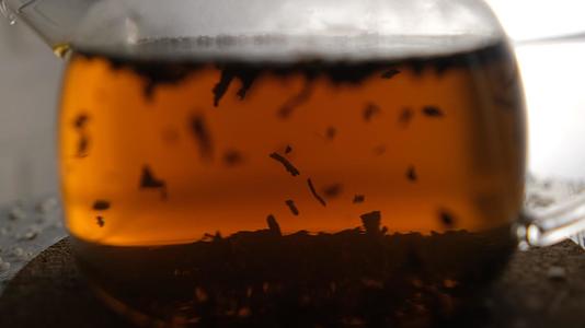 在玻璃茶壶里泡红茶的特写镜头茶在灯光下玩耍视频的预览图
