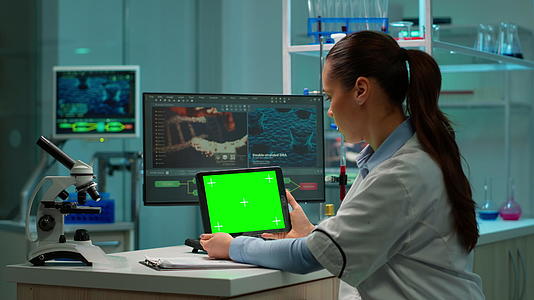 生物化学家坐在实验室里使用绿色模拟屏幕板视频的预览图